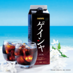 Carton of Doutor coffee beside two glasses of iced coffee on a beach with white flowers in the foreground