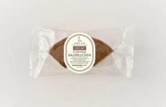 Single packaged decaf coffee Baumkuchen cookie in a clear plastic wrapper with a circular label reading 'Decaf Coffee Baumkuchen' on top of the cookie