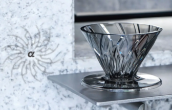 Faceted glass bowl with a wide opening sits on a metal display shelf against a textured gray wall