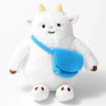 White plush monster with yellow horns brown feet and a blue crossbody bag facing forward with a friendly smile