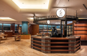 Circular coffee bar with a brick and wood counter surrounded by a ring sign that reads COFFEE BEANS with a Seagaia logo bookshelves and displays in the background