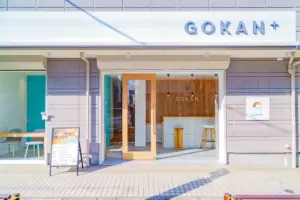 Shopfront of GOKAN+ with wooden framed glass doors and a white brick counter visible inside