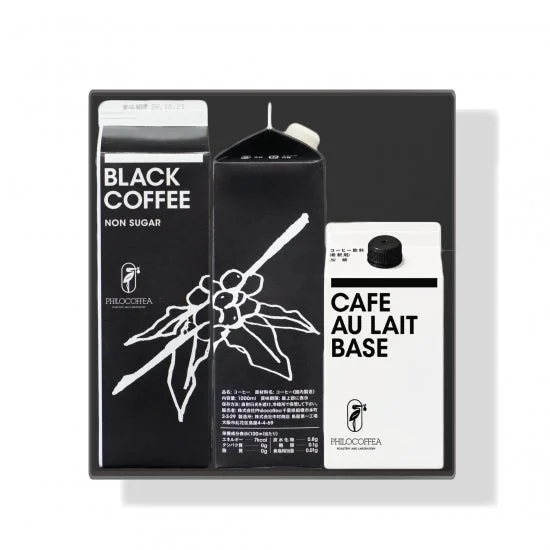 Tray containing three beverage cartons a black coffee non sugar carton on the left a tall black bottle in the center and a cafe au lait base carton on the right all feature the Philocoffea branding and white text