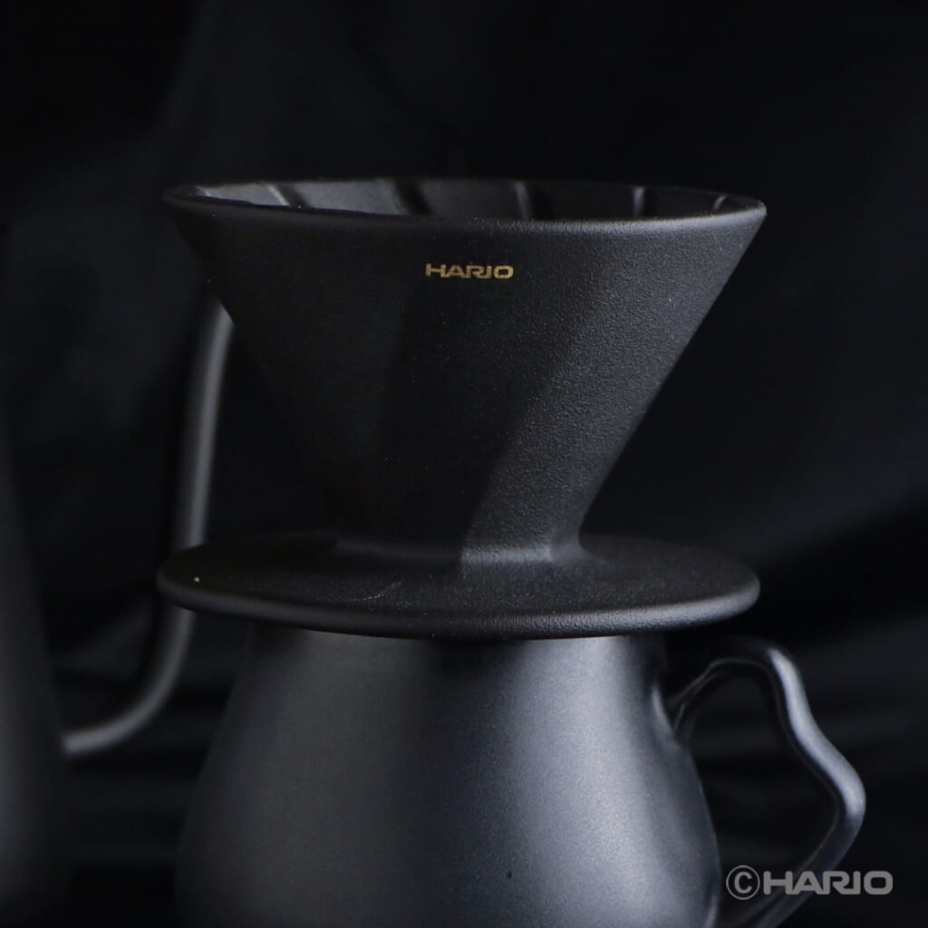 Close up of a black Hario V60 pour over dripper on a kettle with gold HARIO logo