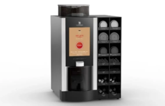 Modern coffee vending machine with a central display and a vertical rack of capsule holders on the right.
