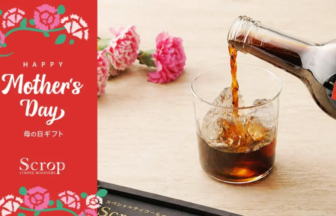 Mother's Day gift card with floral design beside a glass of iced cola on a wooden table.