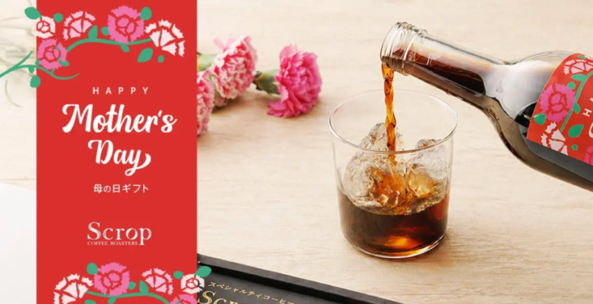 Mothers Day gift card with floral design beside a glass of iced cola on a wooden table