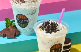 Two Tully's Coffee frappes topped with whipped cream and cookie crumbles on a colorful backdrop; pastel hues and cookies nearby.