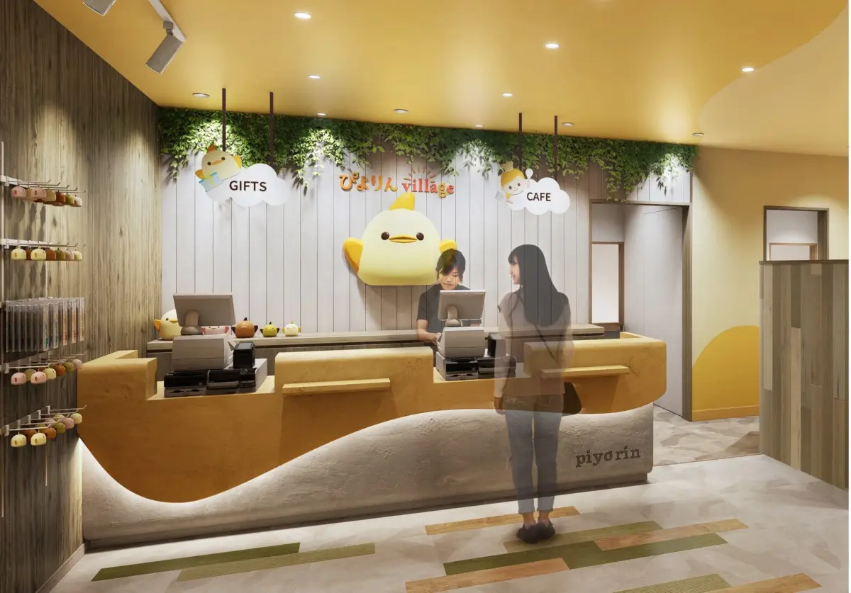 ぴよりんキャラクターをテーマにしたカフェ兼ギフトショップの店内風景です。カウンターにはスタッフがおり、お客様が買い物やサービスを受けています。かわいらしいひよこの装飾が特徴的です。
