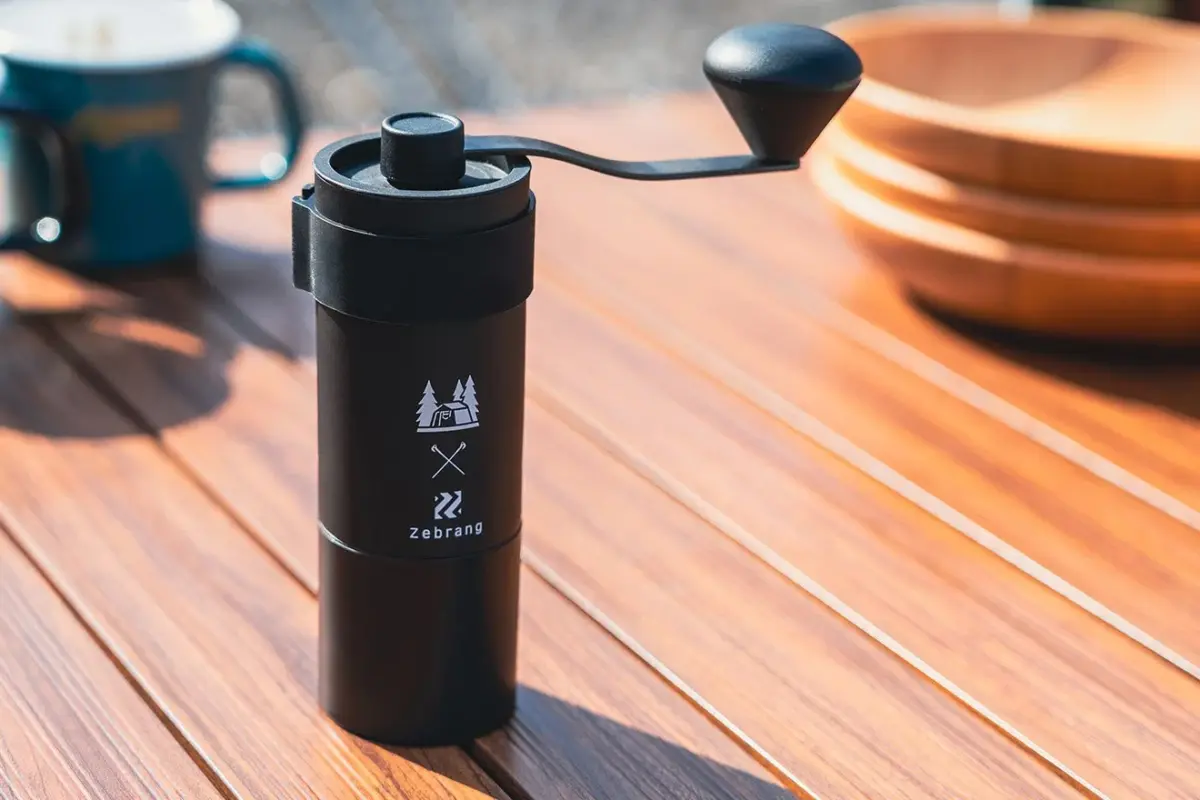 Black camping water bottle with a flip top cap on a wooden table outdoors brand logo and trees visible on the bottle