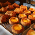 Assorted pastries on a bakery display rack including croissants and cream filled Danish pastries sultry with flaky layers