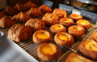 Assorted pastries on a bakery display rack, including croissants and cream-filled Danish pastries sultry with flaky layers.