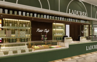 Ladurée counter inside a green Parisian inspired storefront with displays of macarons and pastries under warm lighting and a Petit Café sign in the back room