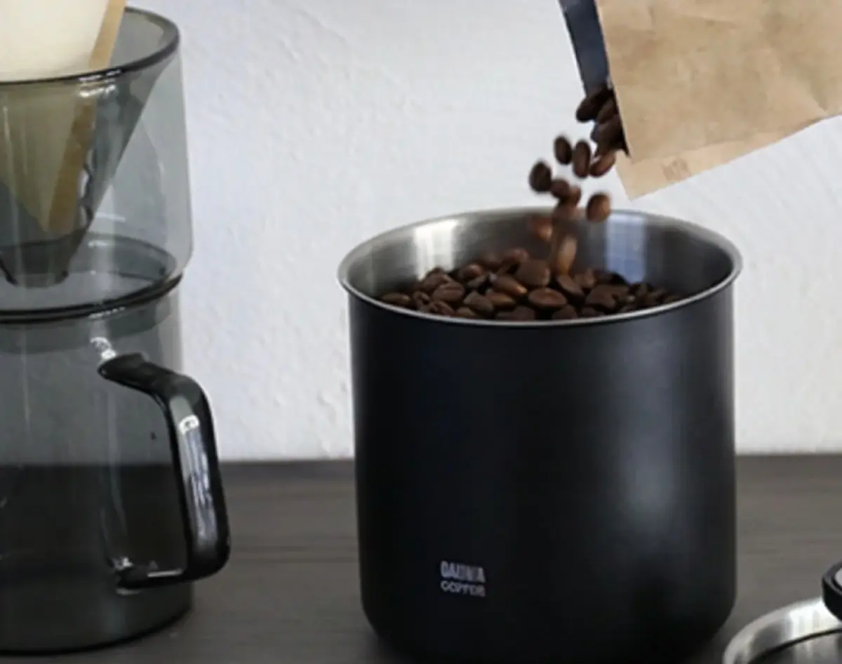コーヒー豆を紙袋から容器に注ぐ様子