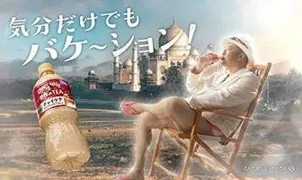 Humorous ad scene a man relaxing in a deck chair with a giant bottle of tea floating beside him Japanese text overhead and a factory skyline in the background
