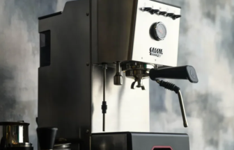 Professional espresso machine on a cafe counter with a portafilter attached and a steam wand ready for steaming.