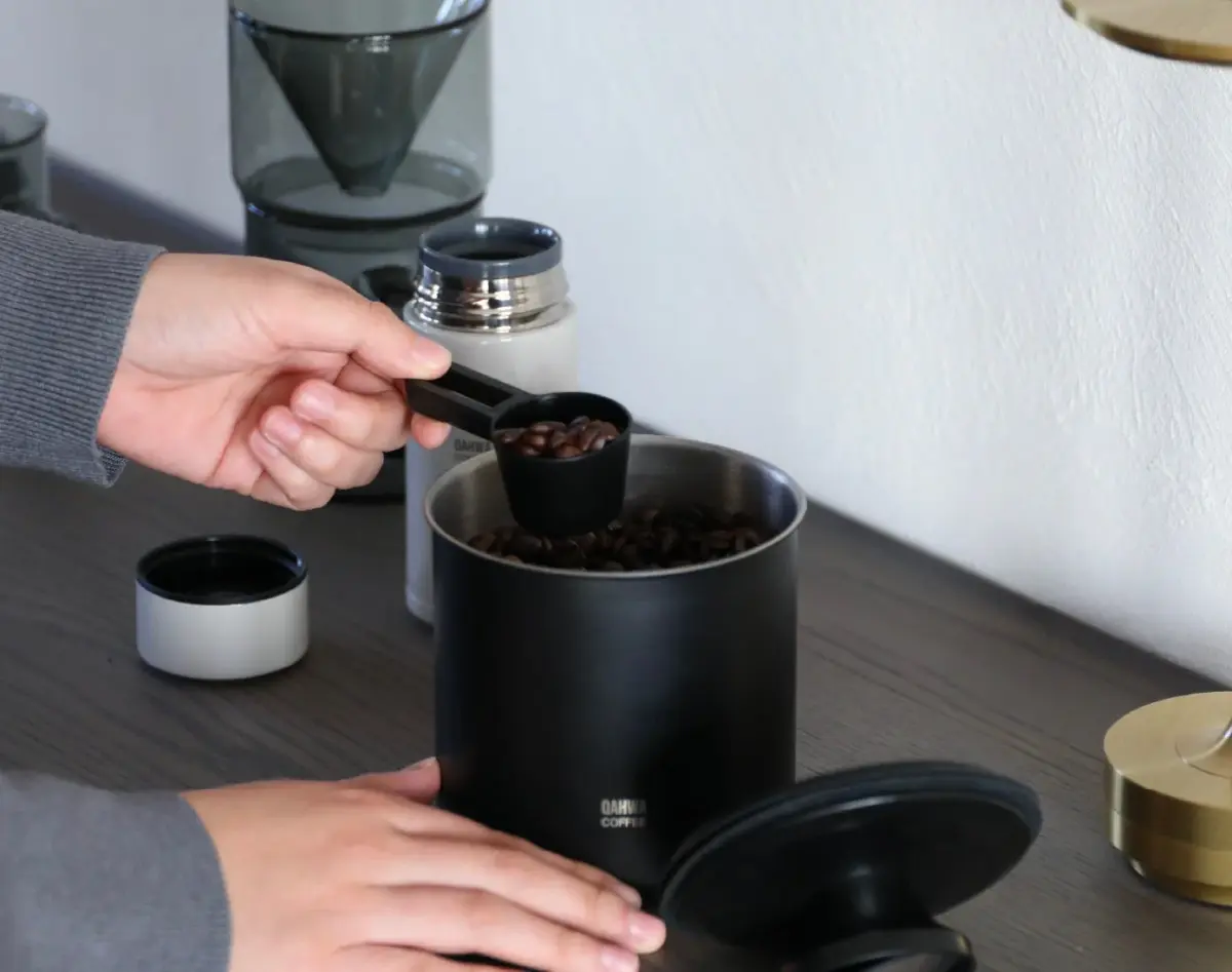コーヒー豆をスクープで計量し、容器から取り出している様子
