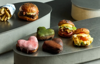 Assorted mini burgers and heart-shaped donuts displayed on a curved metal platform.