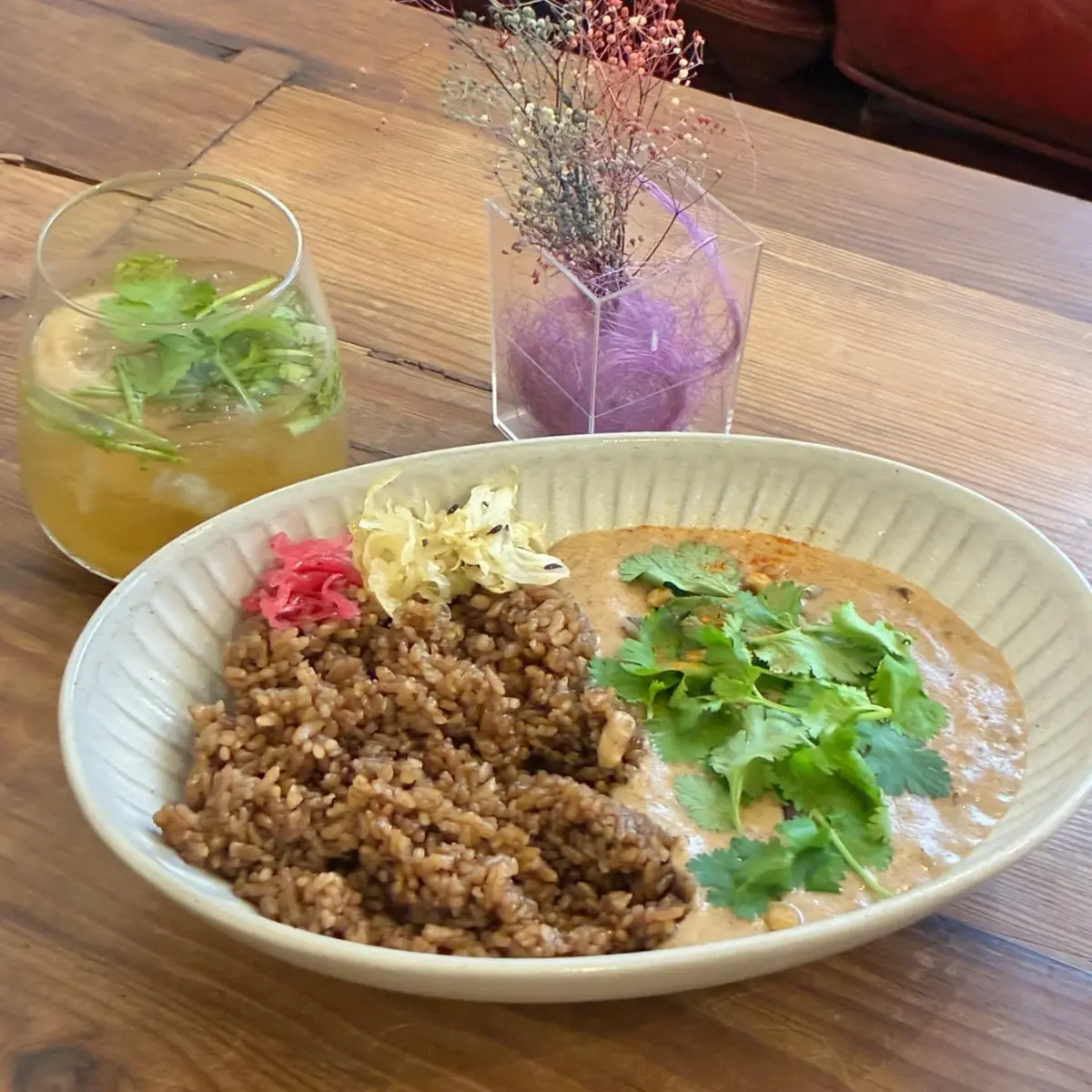 木製のテーブルに置かれた、パクチーが添えられたカレーライス