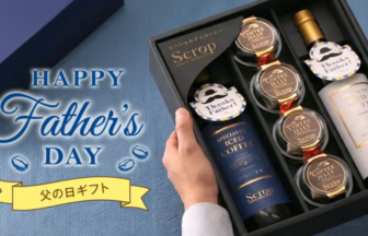 Fathers Day gift set in a black box with multiple coffee jars and a bottle held by hands against a blue background