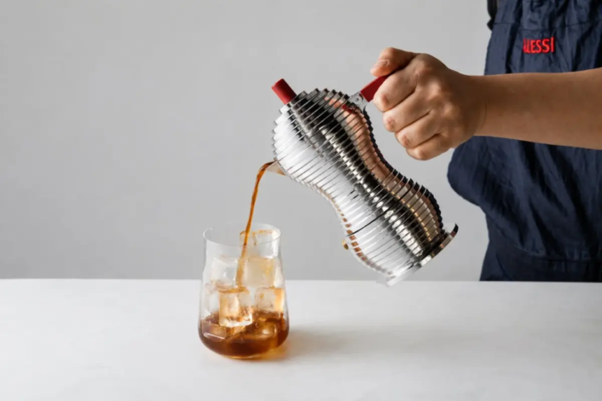 Barista pours coffee from a stainless steel vacuum siphon into a glass with ice