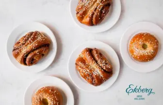 Top-down view of assorted pastries—twisted cinnamon buns and ring donuts—on small white plates with a light background.