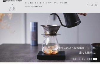 Pour-over coffee setup with a glass carafe on a black scale as hot water pours from a kettle over it on a kitchen counter.
