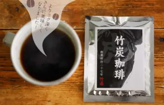 Cup of black coffee steaming beside a silver package labeled 竹炭咖啡 on a wooden table