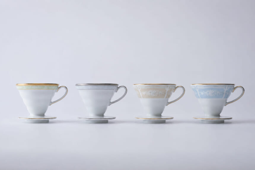 Four delicate teacups with saucers in pastel colors lined up on a white surface green gray beige blue