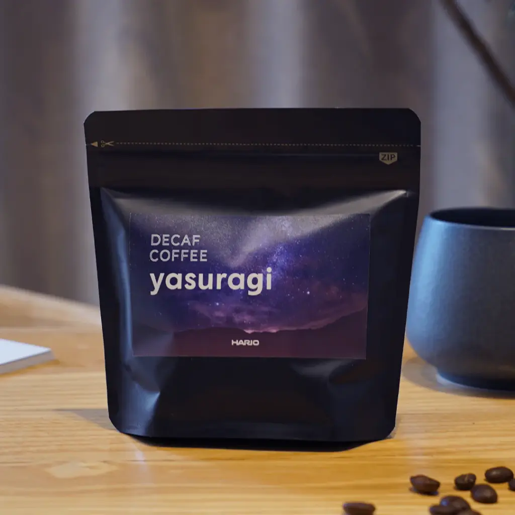 yasuragiimagesquare | コーヒーステーション Black resealable coffee bag labeled Decaf Coffee Yasuragi by Hario on a wooden table