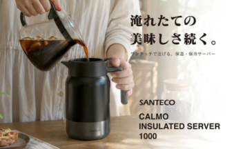 Person pours hot coffee from a glass carafe into a black Santeco Calmo insulated server on a wooden table poster.