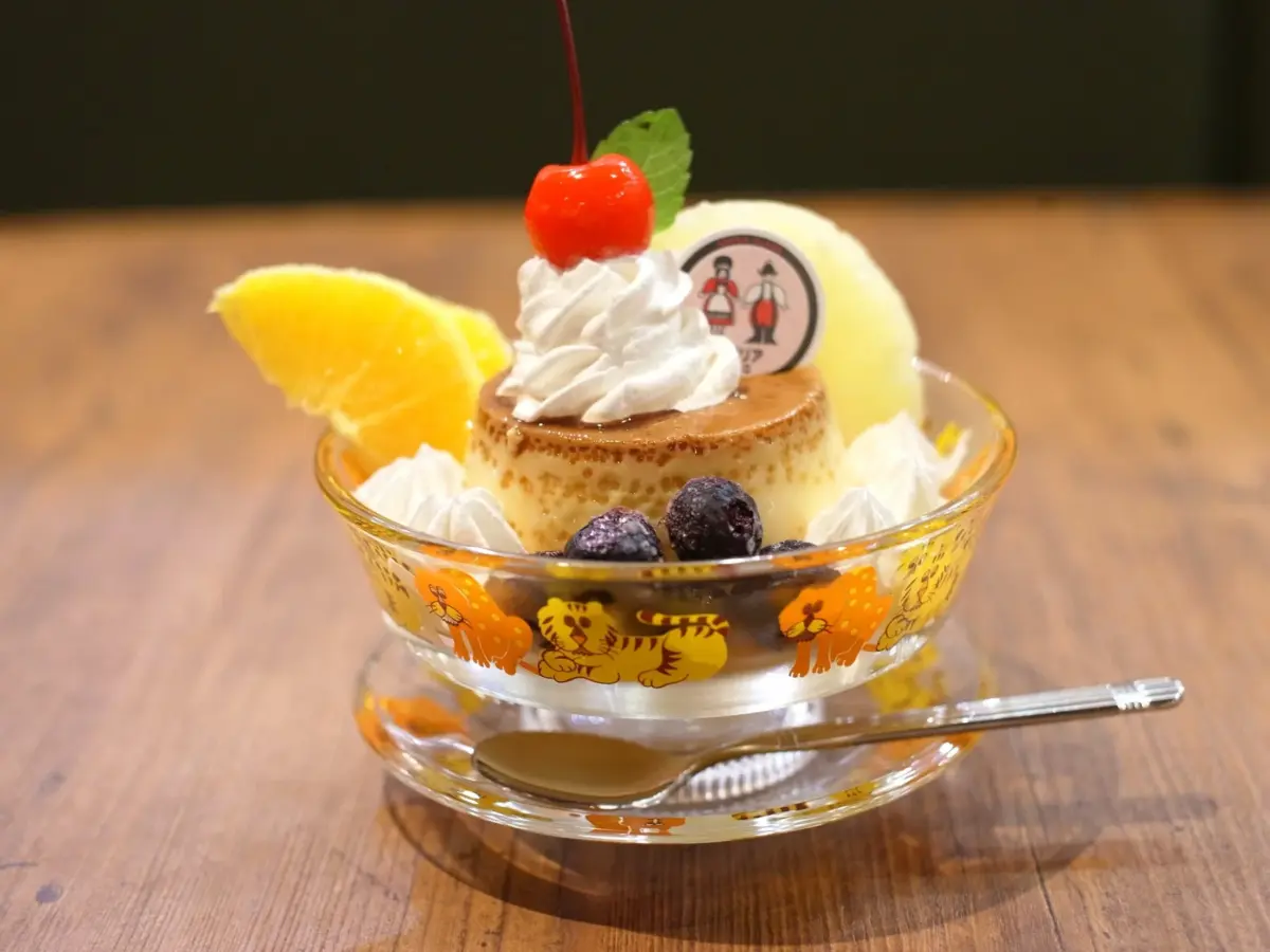 木製のテーブルに置かれたプリンを中心としたグラスデザートです。