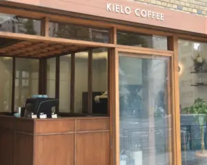 Wood framed coffee shop storefront with KIELO COFFEE sign interior shows a counter and an espresso machine