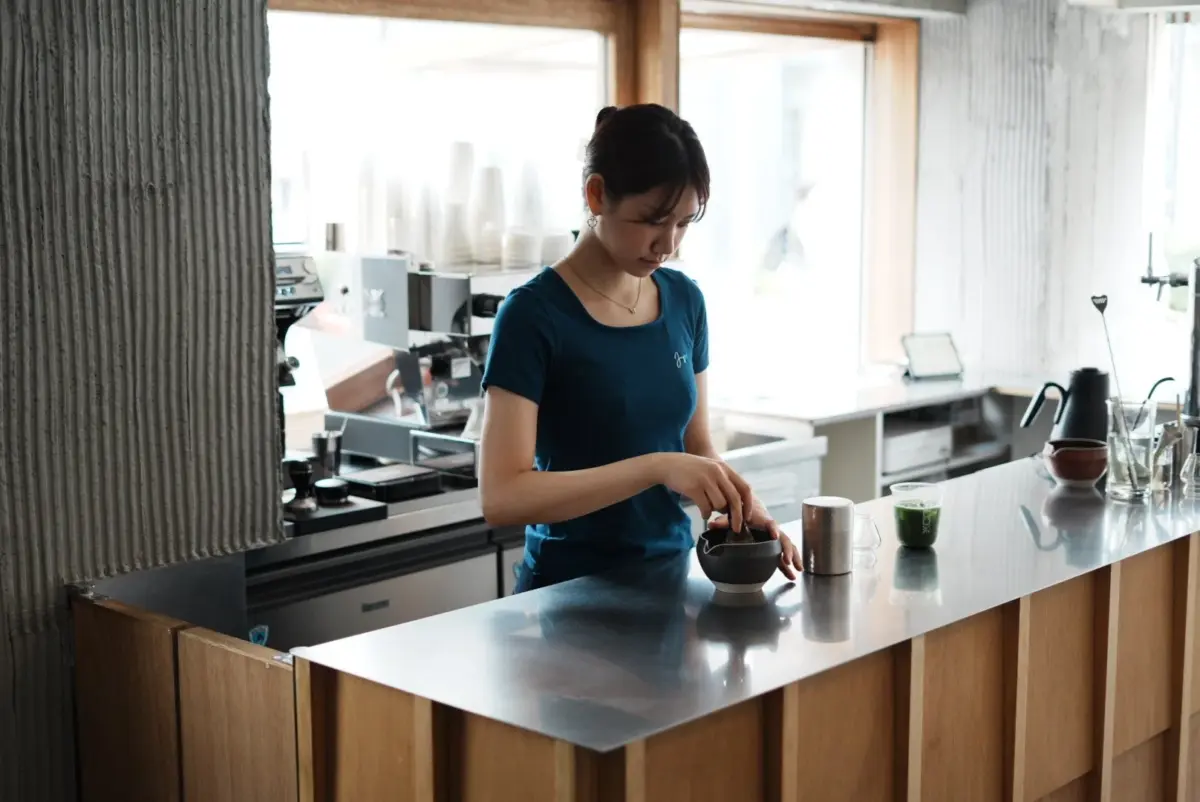 カフェのカウンターで抹茶を準備する女性