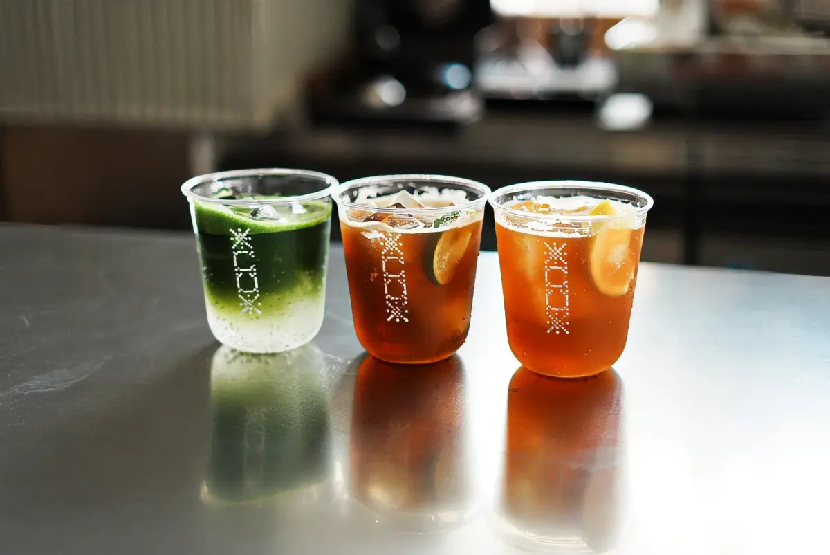 カウンターに並べられた3つの冷たいドリンク、抹茶とレモンのカクテル