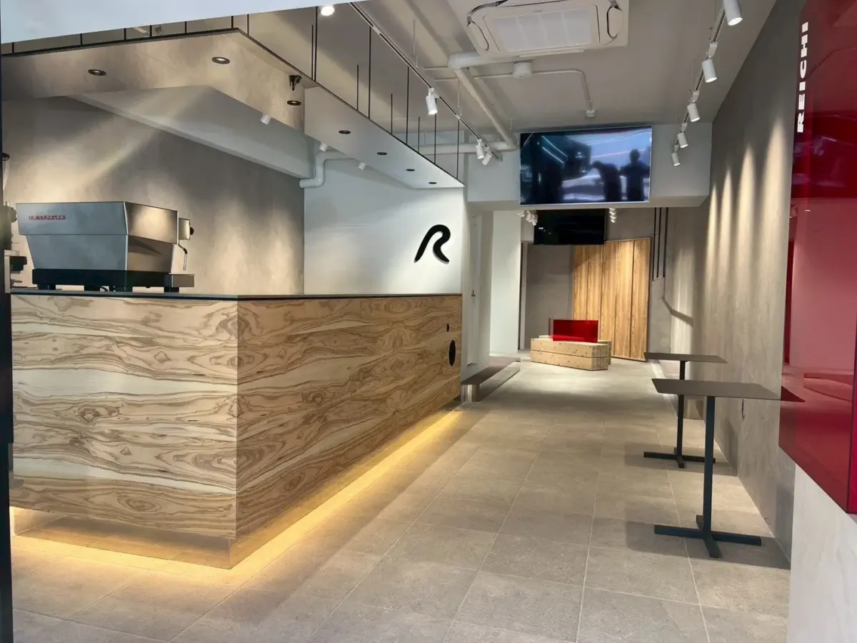 Modern cafe interior with a wood paneled counter warm under counter lighting gray tile floor and a logo on the back wall