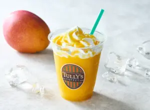 Mango smoothie in a clear cup with whipped cream and a green straw Tullys Coffee logo visible