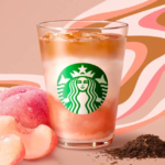 Starbucks iced peach flavored drink in a glass with peaches and loose tea leaves on a pink patterned backdrop