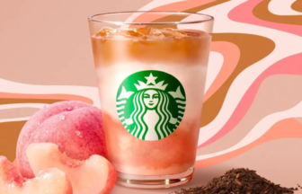 Starbucks iced peach-flavored drink in a glass with peaches and loose tea leaves on a pink-patterned backdrop