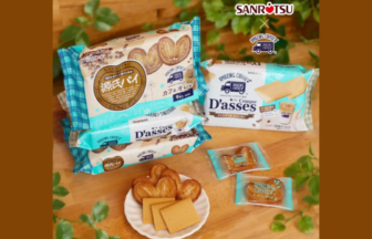 Assorted Sanritsu Dasses cookies in turquoise packaging on a wooden table with a plate of baked treats in the foreground Includes visible product names and wrappers
