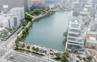 Bird's-eye view of a city river with a tree-lined promenade and modern buildings along the water.