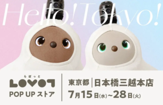 Two LOVOT robot companions in white hooded outfits with pastel pink/blue backdrop, advertising the LOVOT Pop Up Store in Tokyo (July 15–28).