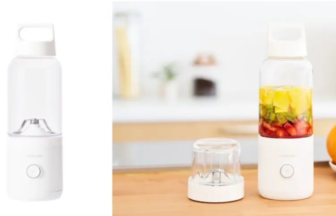 White compact blender with detachable cup and lid placed beside a fruit infuser bottle on a kitchen counter