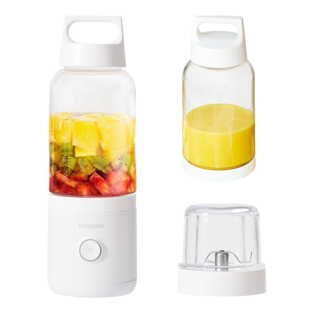 White compact blender with a tall jar filled with chopped fruit pineapple kiwi strawberry and a detachable blade base separate yellow juice cup nearby