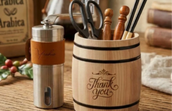 Wood and stainless steel kitchen tools in a carved wooden barrel labeled 'Thank you' on a rustic table.