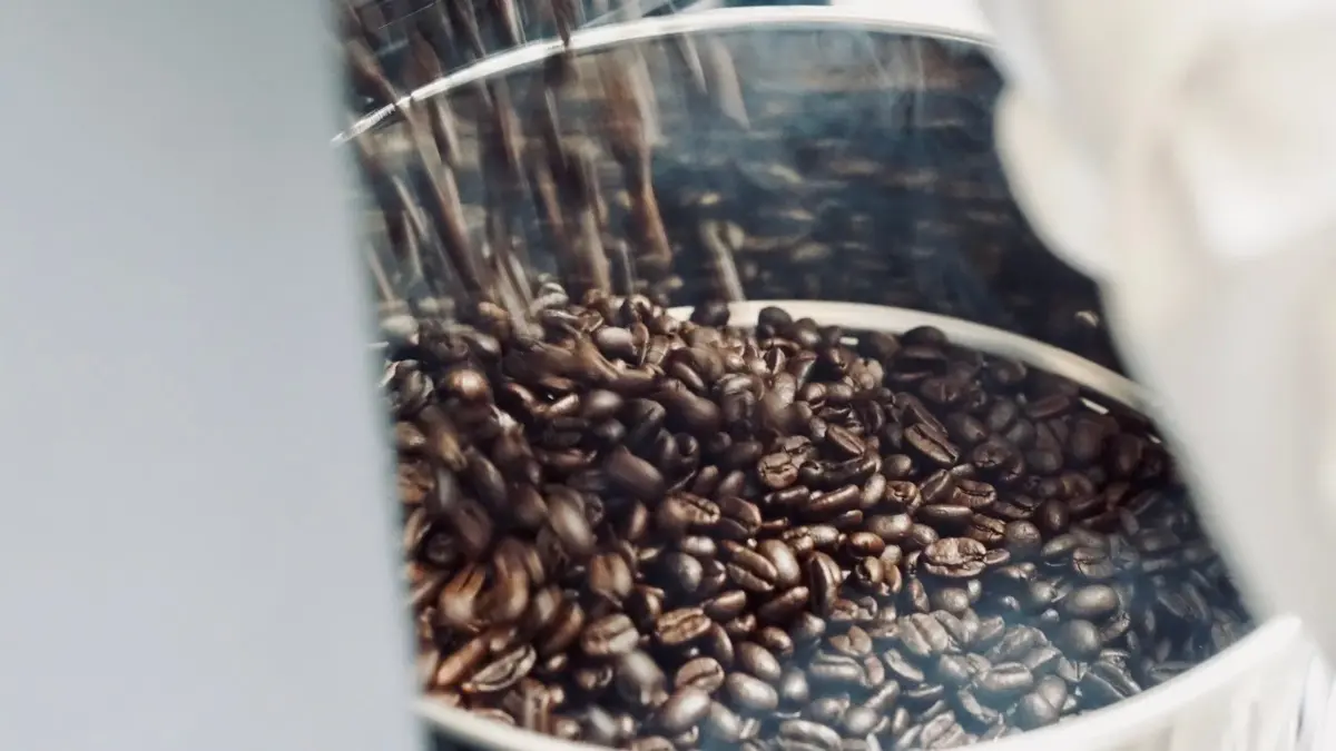 深煎りされたコーヒー豆が、金属製の容器に勢いよく流れ込んでいる様子