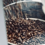 Close up of shiny metal container filled with dark roasted coffee beans