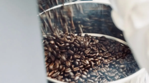 Close up of shiny metal container filled with dark roasted coffee beans