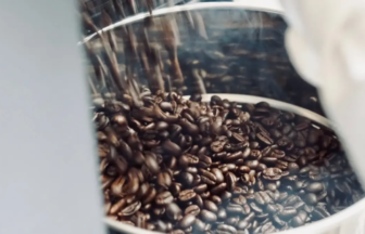 Close-up of shiny metal container filled with dark roasted coffee beans.