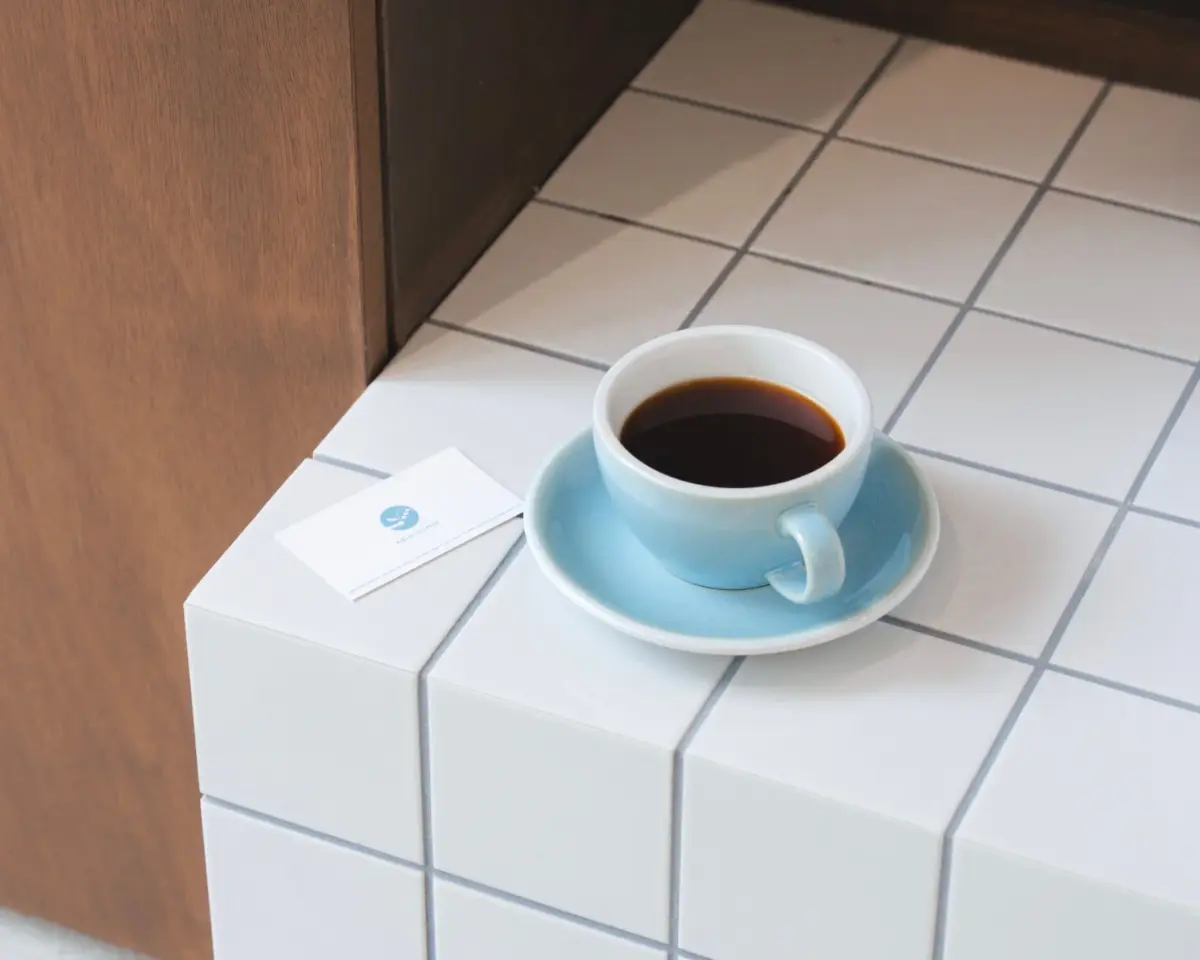 白いタイル張りのカウンターに置かれた水色のコーヒーカップ